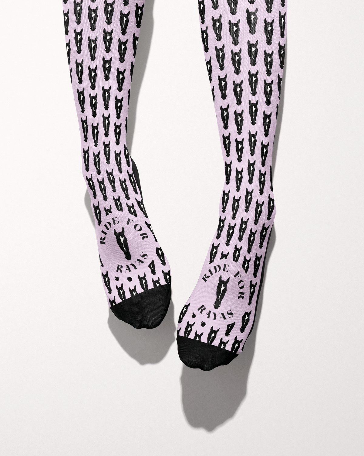Nikko socks seen from the toes, black toe caps and the Ride for Rayas horse logo over the pink horse-head print