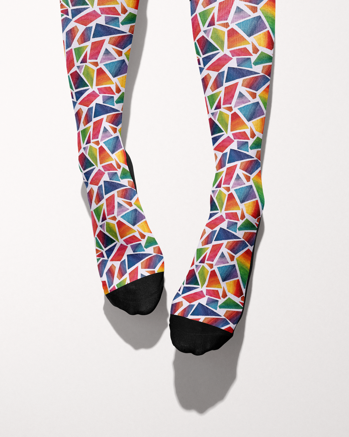 Original Art socks shown from the toes, black toe caps against the red, blue, green and yellow mosaic print