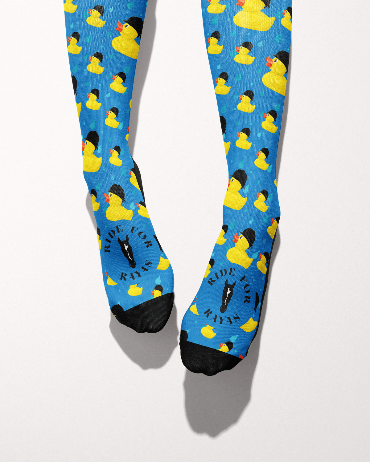 Rubber Ducky socks viewed from the toes, black toe caps and the Ride for Rayas horse logo on the blue duck print