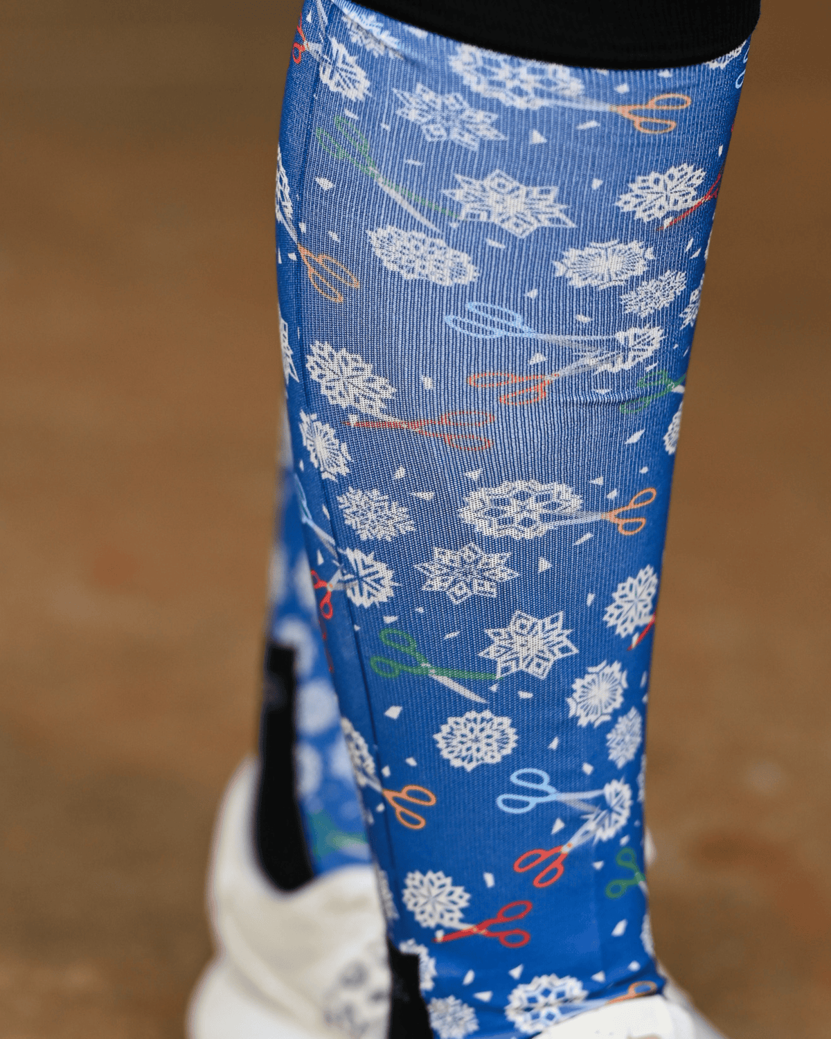 Close crop of the Shear Magic boot sock print, white clip rosettes and coloured scissors on cobalt blue