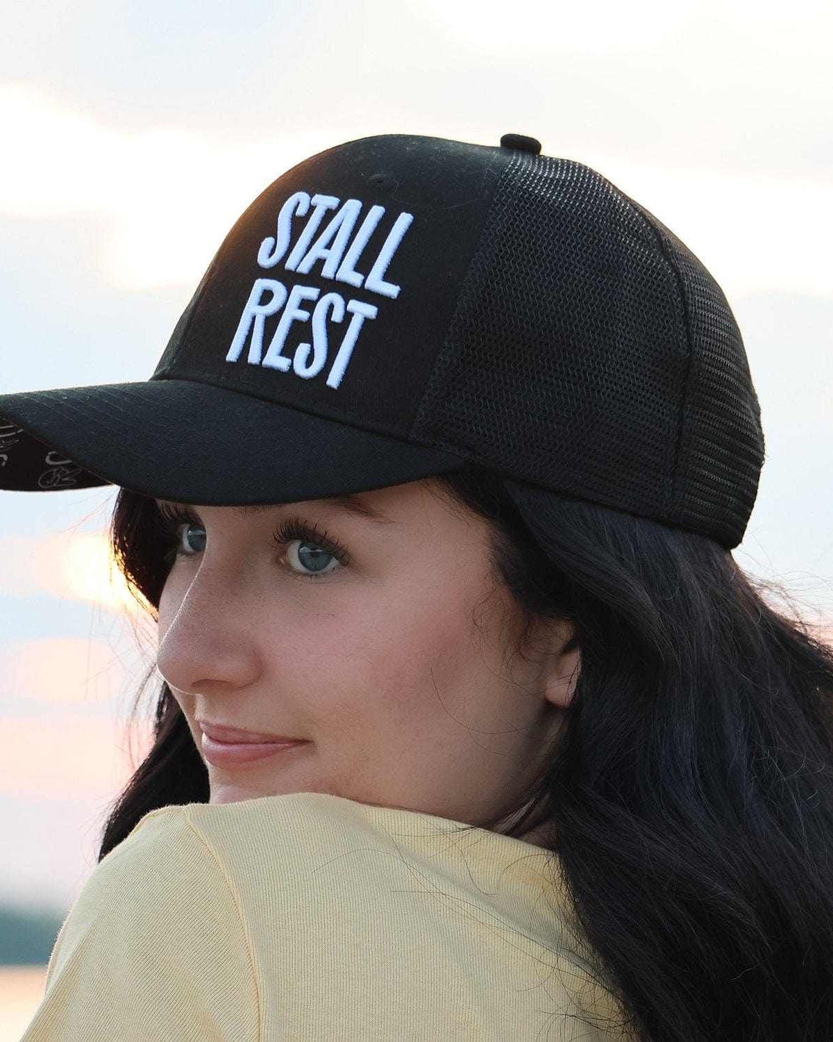 Woman wearing black Stall Rest trucker hat from equestrian bundle