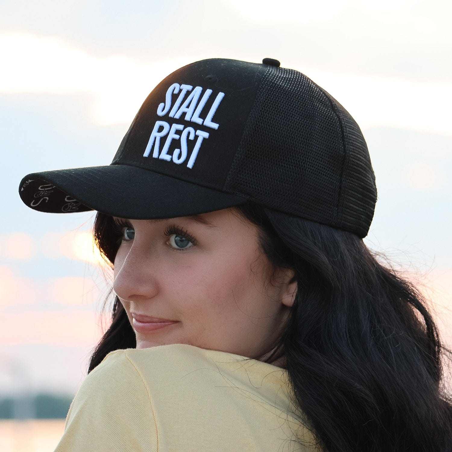 Woman wearing black Stall Rest trucker hat from equestrian bundle
