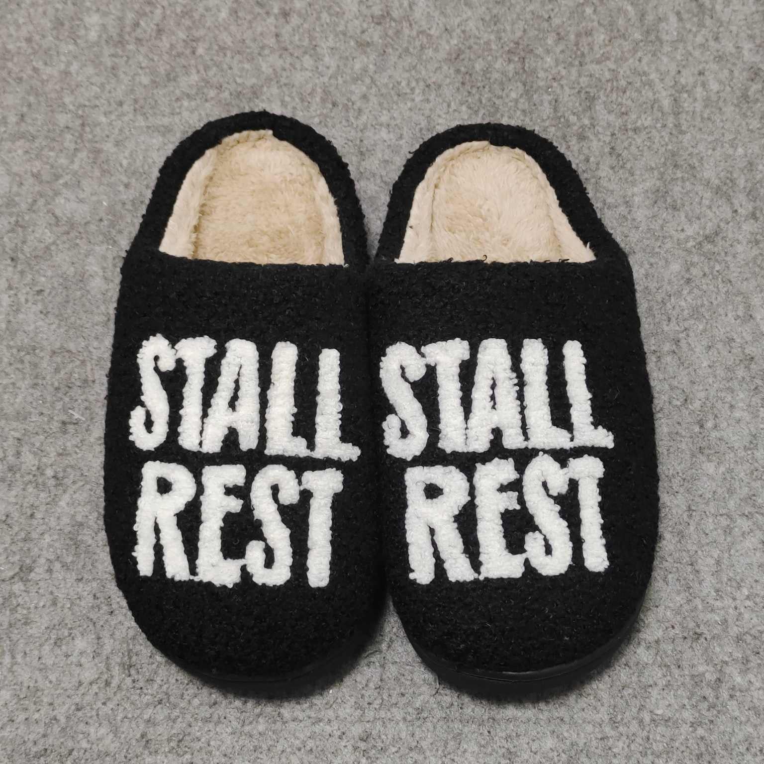 Black plush slippers with "STALL REST" text, part of the Stall Rest Equestrian Bundle for rider comfort and relaxation