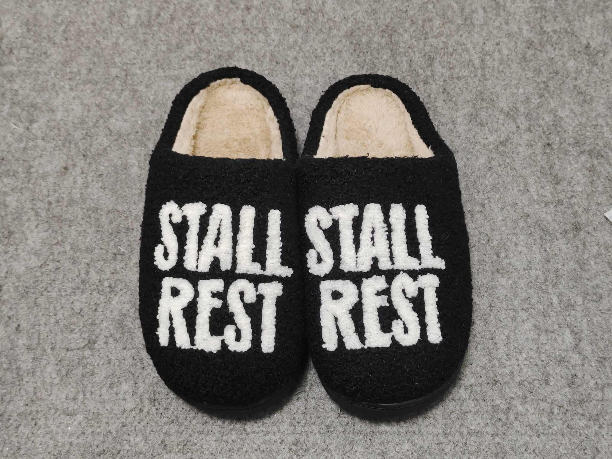 Black plush slippers with "STALL REST" text, part of the Stall Rest Equestrian Bundle for rider comfort and relaxation