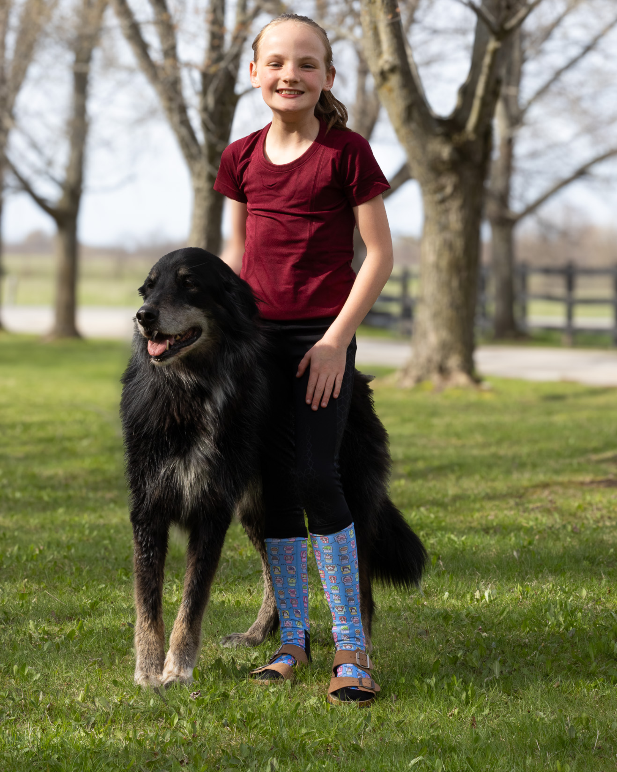 young rider wearing dreamers & schemers equestrian boot socks while posing with her farm dog at the horse stable