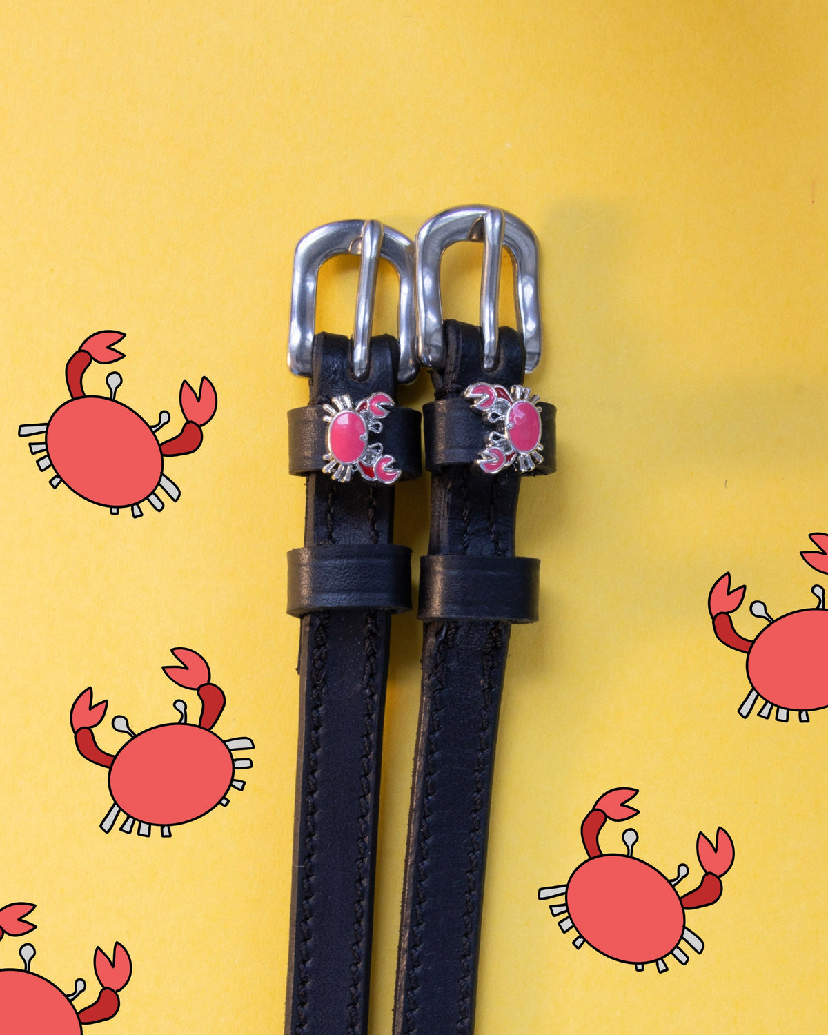 Crabbin' ManeJane spur straps with the signature Crabbin' charm, shown on a yellow background, by Dreamers & Schemers