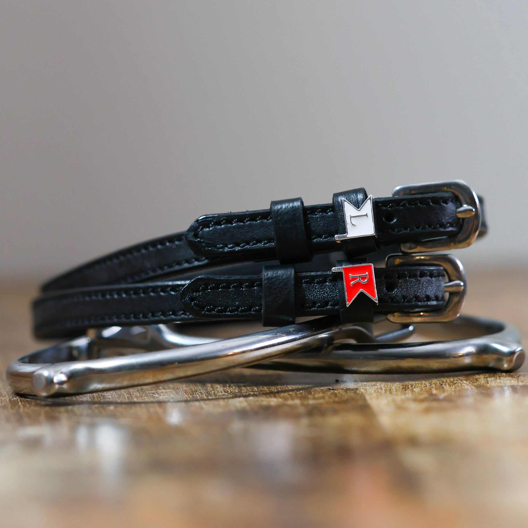 Black leather Jump Flags Spur Straps with stainless steel buckle and custom charm on peg wall display