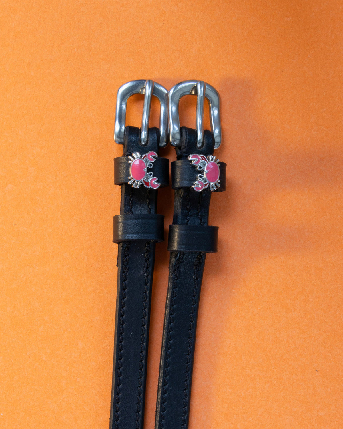 Crabbin' ManeJane spur straps with the signature Crabbin' charm, shown on an orange background