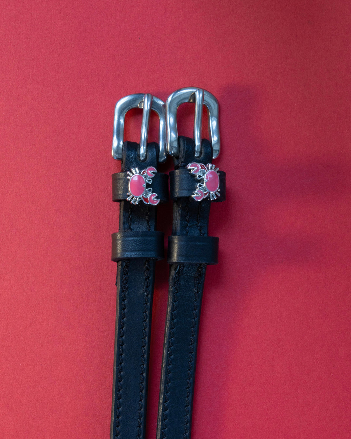 Crabbin' ManeJane spur straps with the signature Crabbin' charm, shown on a red background