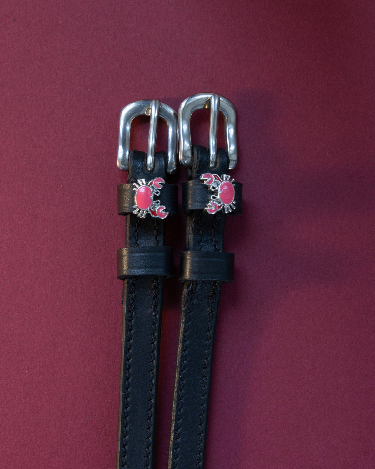 Crabbin' ManeJane spur straps with the signature Crabbin' charm, shown on a plum background