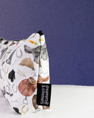 The Hunt zip pouch standing on its gusset, showing the side panel and the woven dreamers & schemers tag