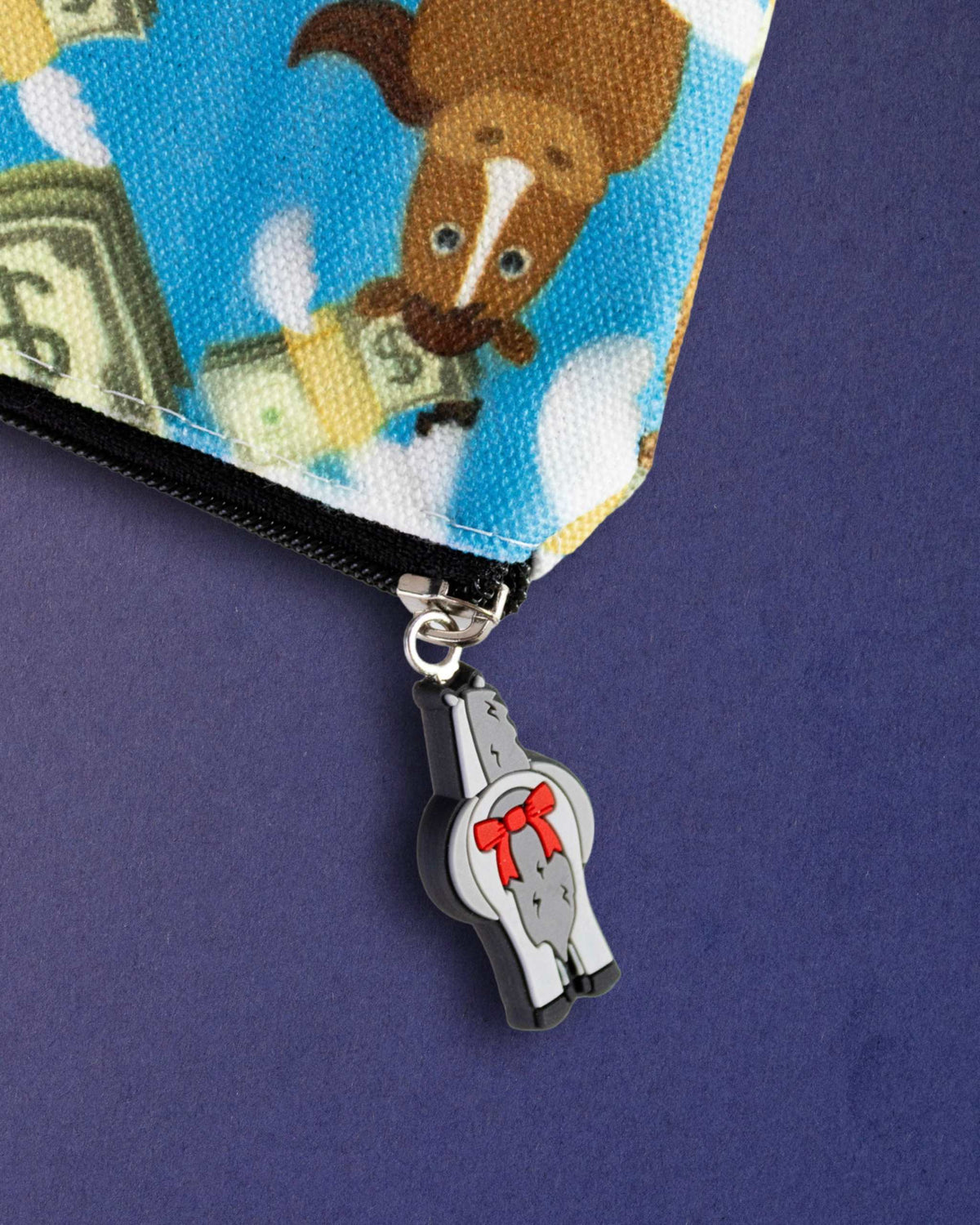 Close-up of the bad pony zip pull, a grey horse charm with a red bow, on the Cash Money pouch