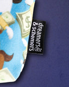 Woven dreamers & schemers label at the seam of the Cash Money pouch, dollar-bill print behind
