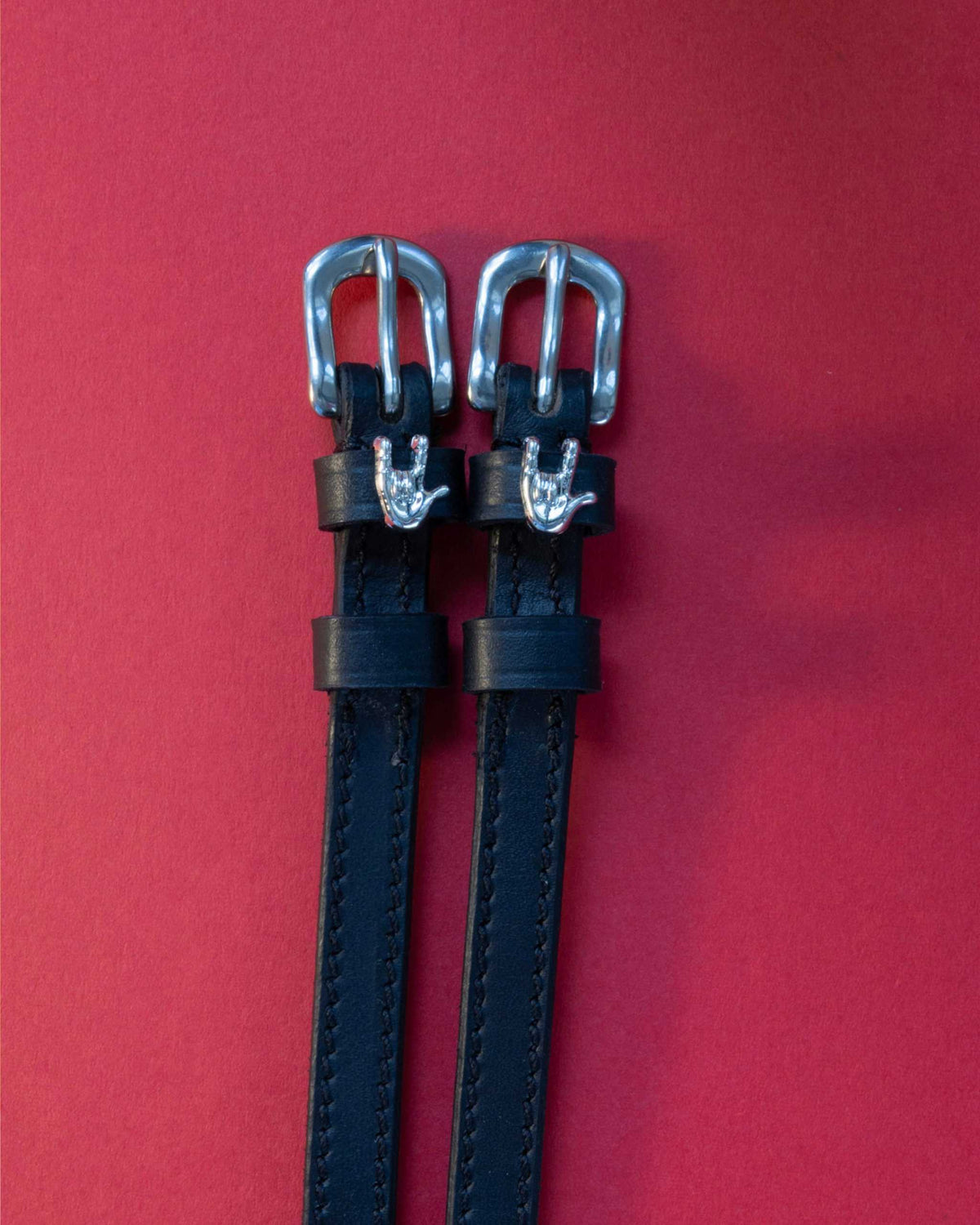 Rock On ManeJane spur straps with the signature Rock On charm, shown on a red background