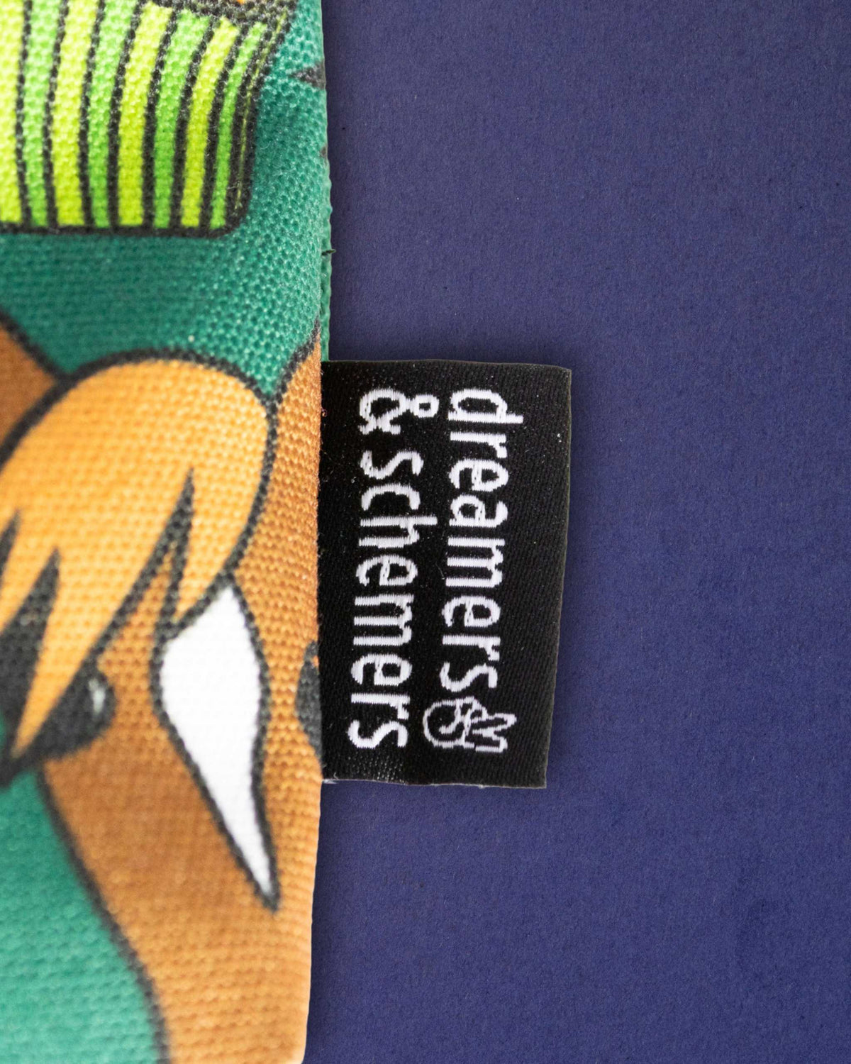 Woven dreamers & schemers tag stitched to the Carrot Cake pouch, chestnut pony print behind