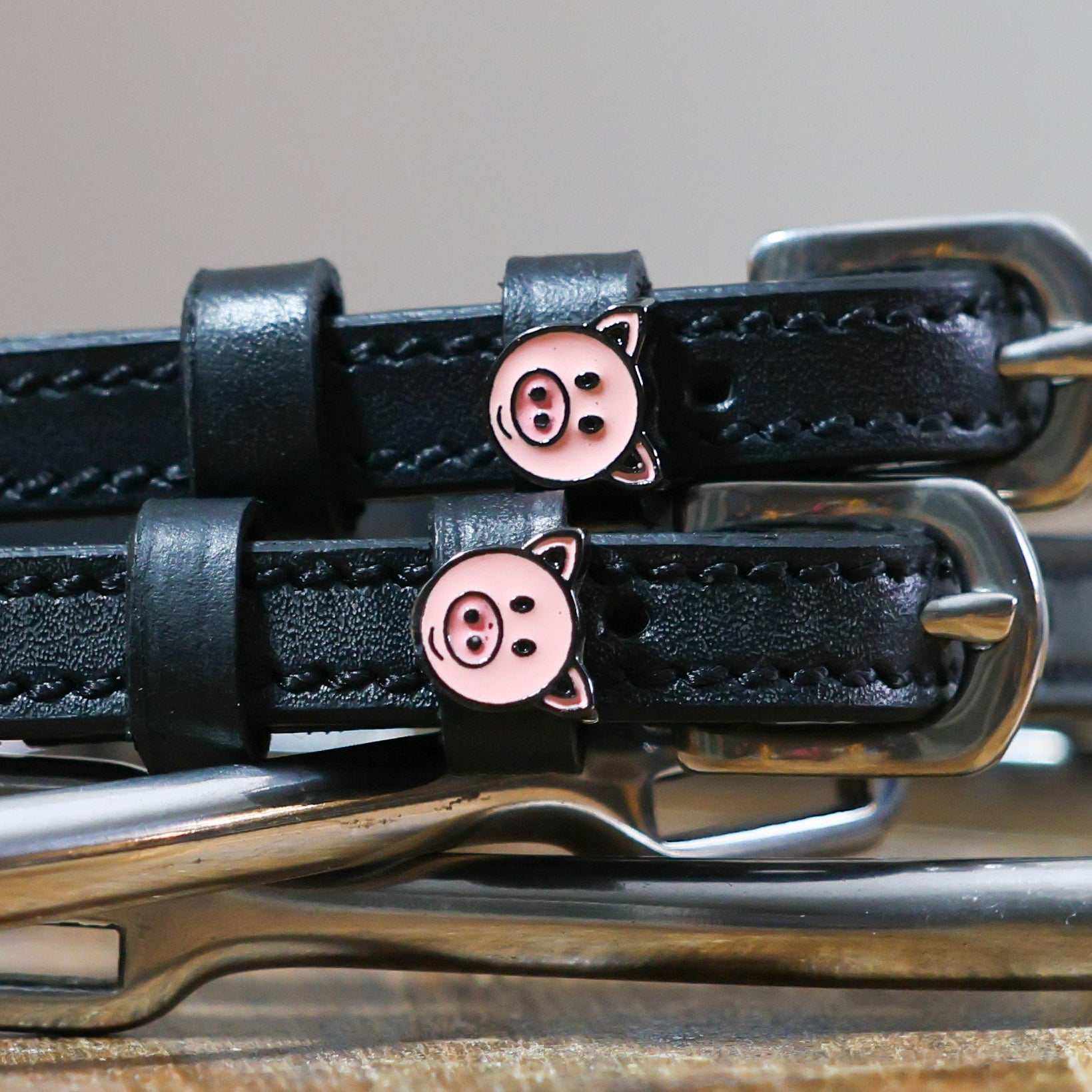 Black leather Piggy Spur Straps with stainless steel buckles and pig charm accents