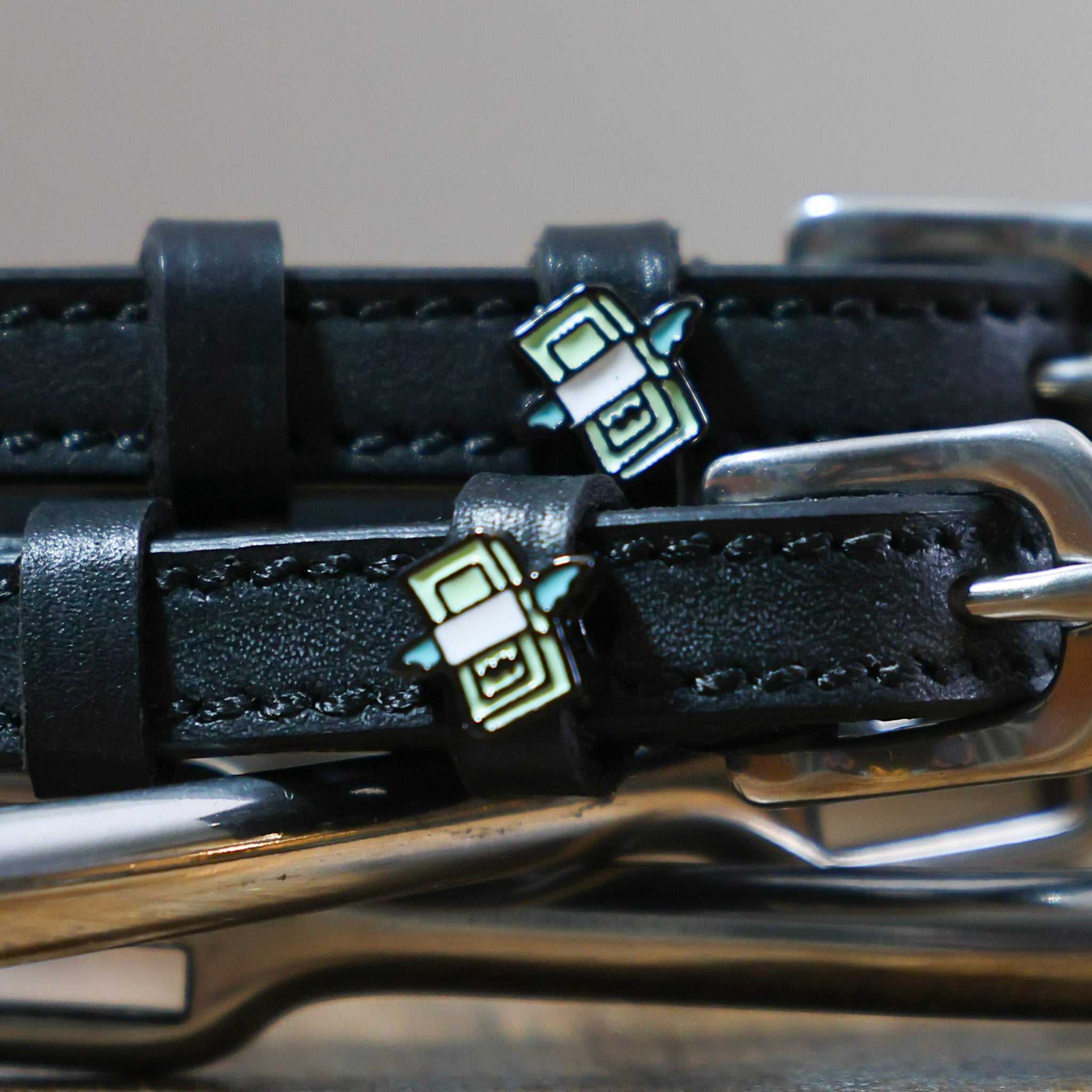 Close-up of black leather Cash Money Spur Straps with stainless steel buckles and custom ManeJane charms