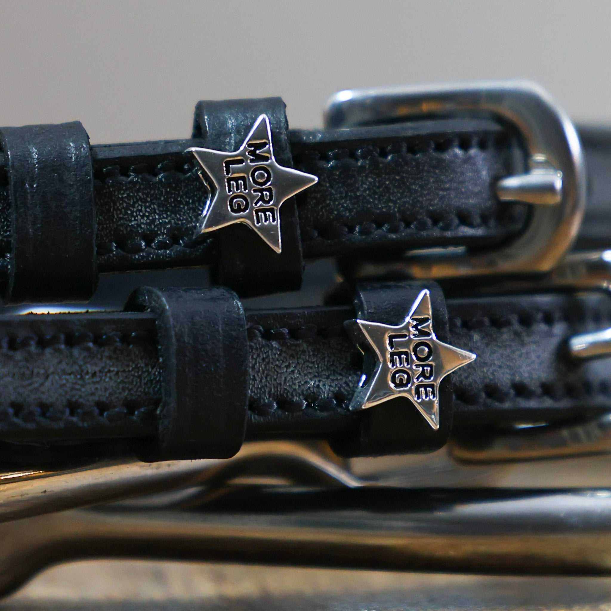Black More Leg Spur Straps with stainless steel buckles and custom star-shaped charms on premium leather