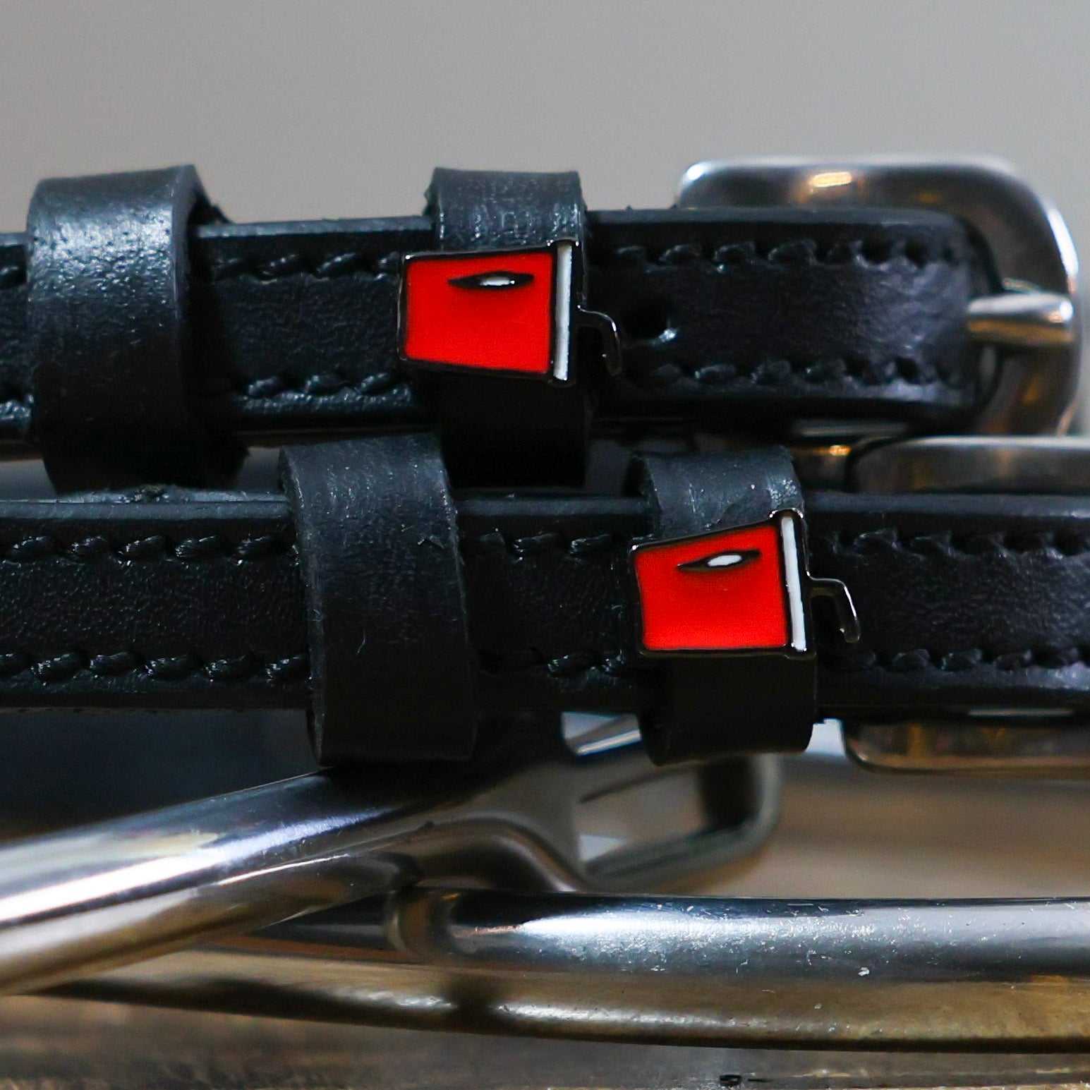 Black leather Soda Spur Straps with stainless steel buckles and red custom charms on horse spurs