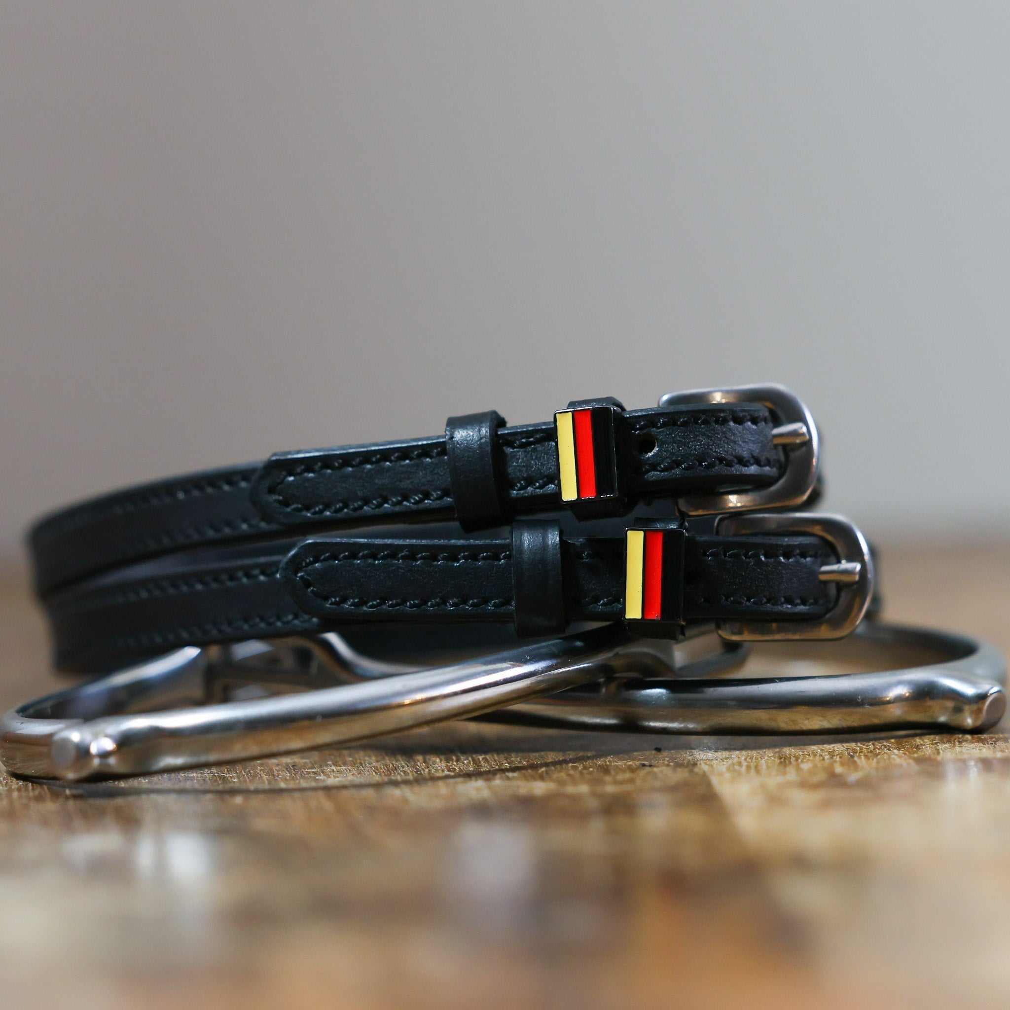 Black leather German Flag Spur Straps with stainless steel buckle and custom charm on peg wall display card