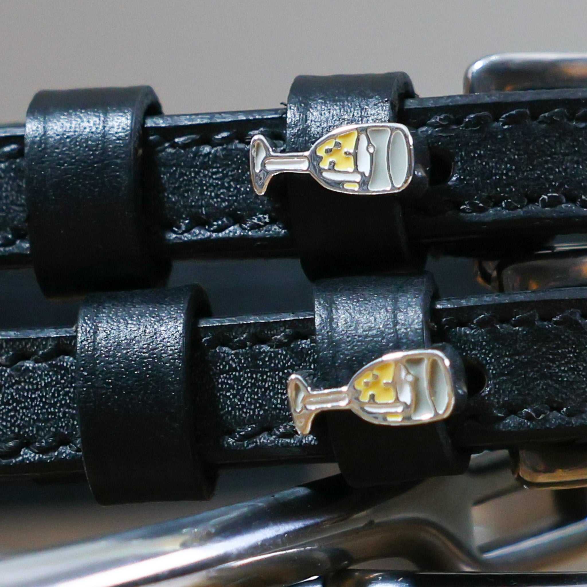 Close-up of black leather Champagne Spur Straps with stainless steel buckles and custom champagne glass charms
