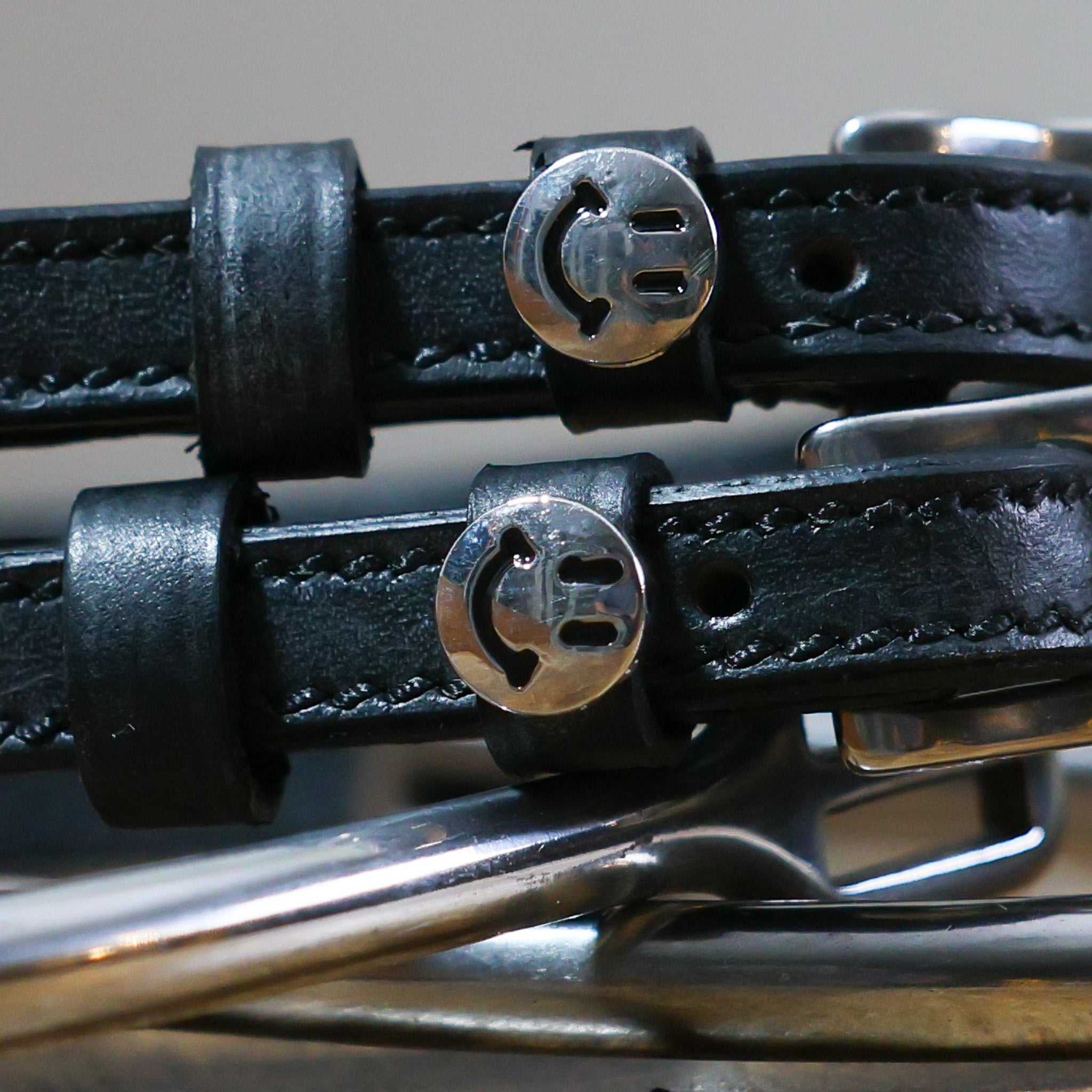 Close-up of black leather Happy Face Spur Straps with stainless steel smiley face charm and buckle