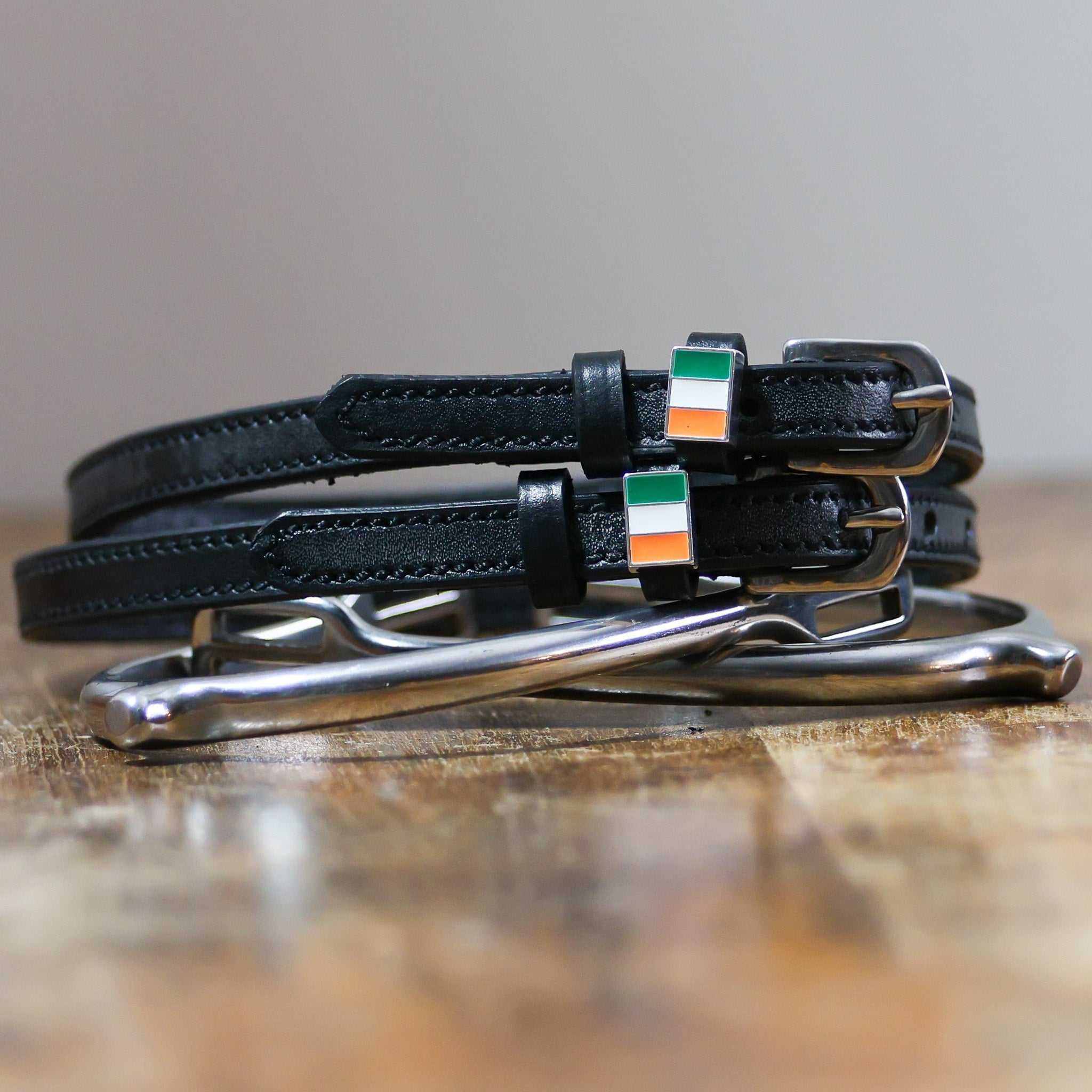 Black leather Irish spur straps with stainless steel buckle and custom charm displayed on peg wall cards
