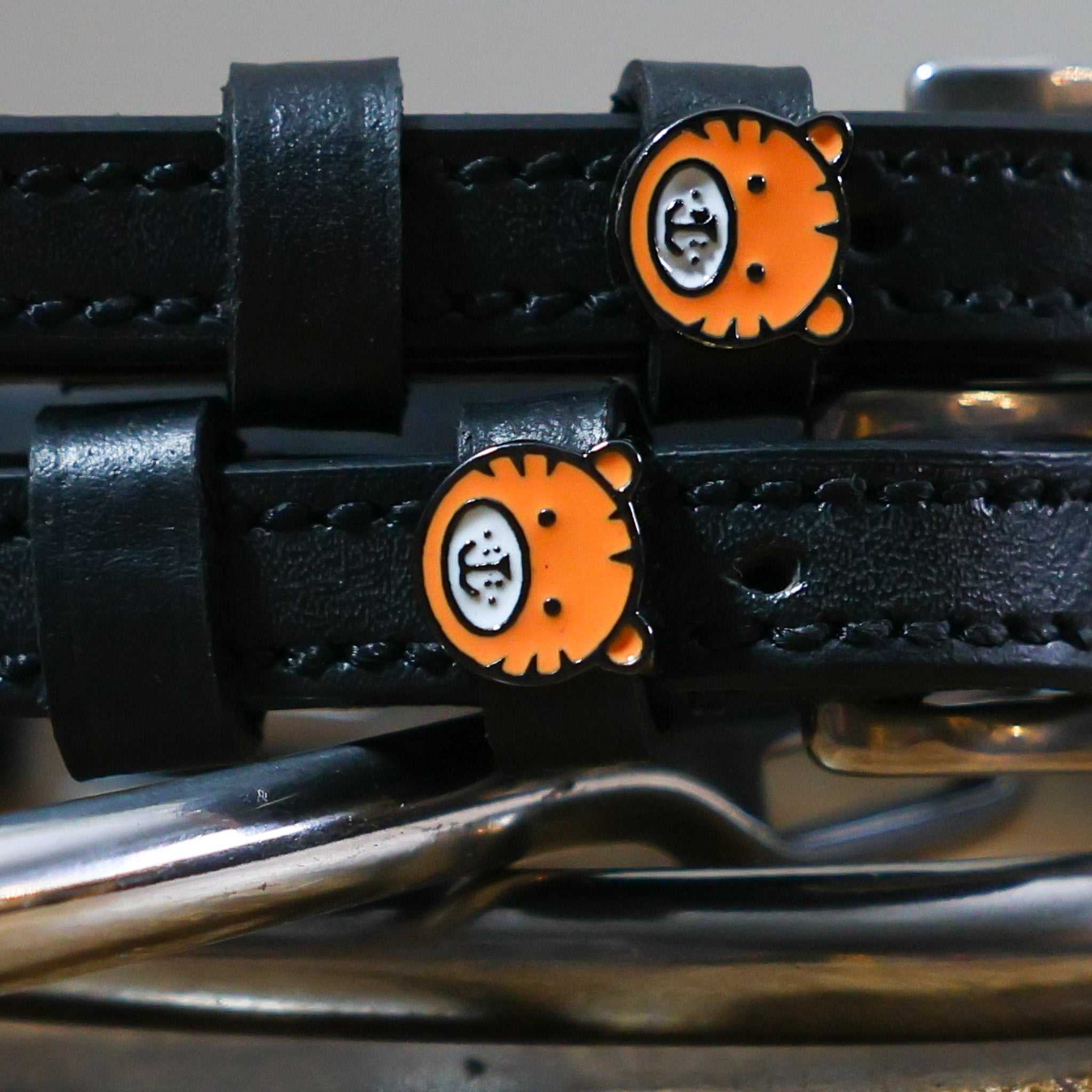 Black leather Tiger Spur Straps with non-stretch interior, stainless steel buckles, and custom tiger charm