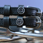 Close-up of black leather Taurus Spur Straps with stainless steel buckles and custom charm on metal spurs