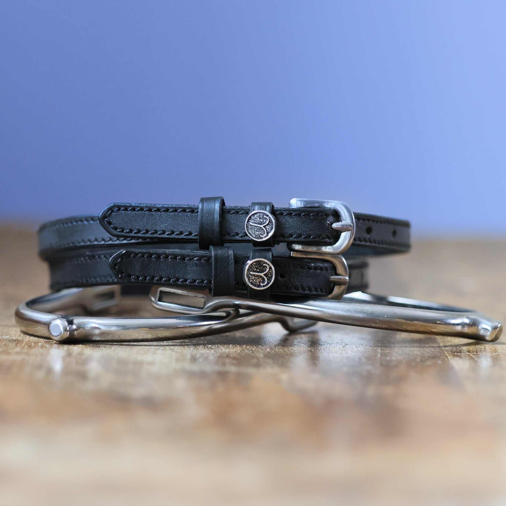 Black leather Aries Spur Straps with stainless steel buckles and custom ManeJane charm