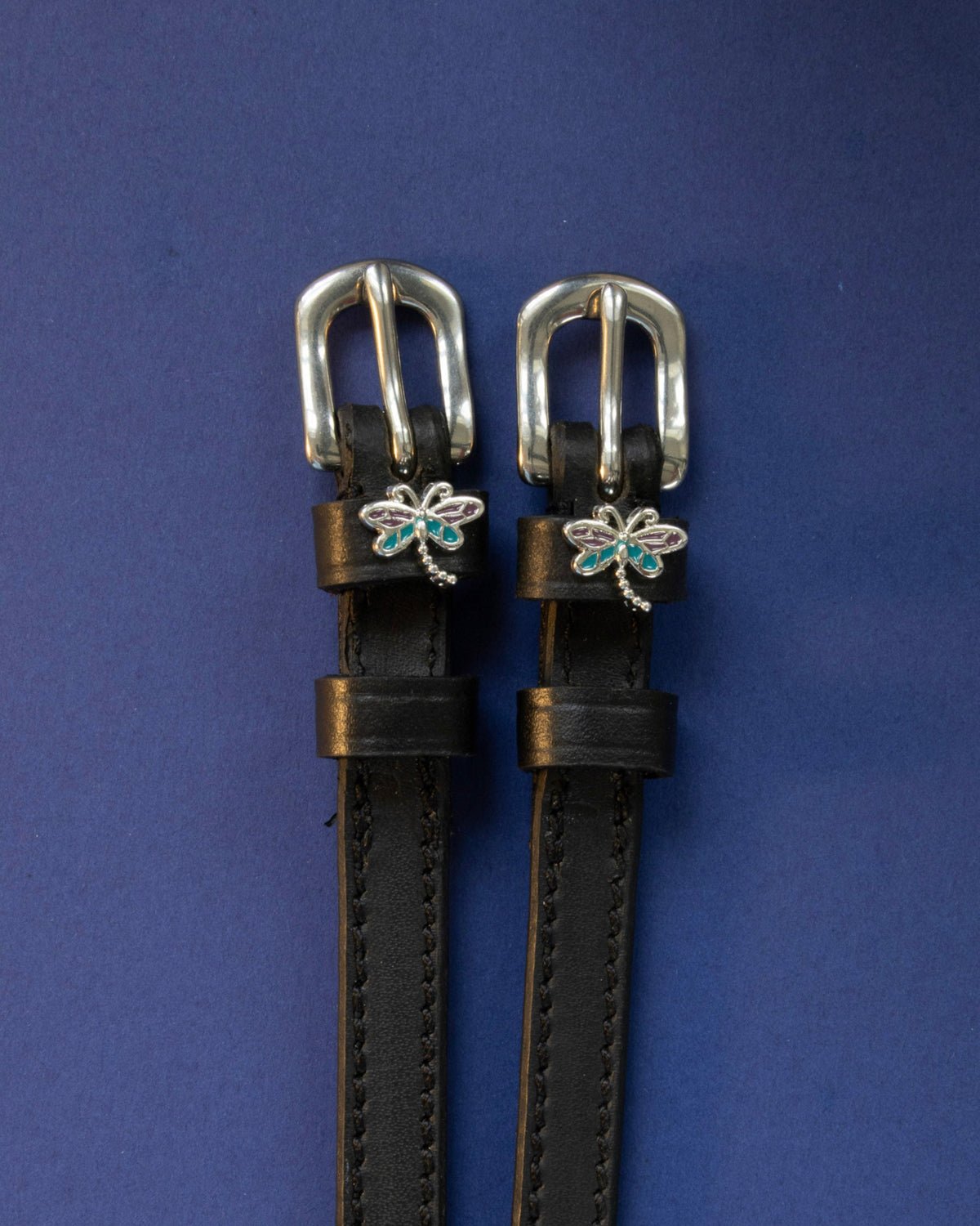 Dragonfly ManeJane spur straps with the signature Dragonfly charm, shown on a navy background