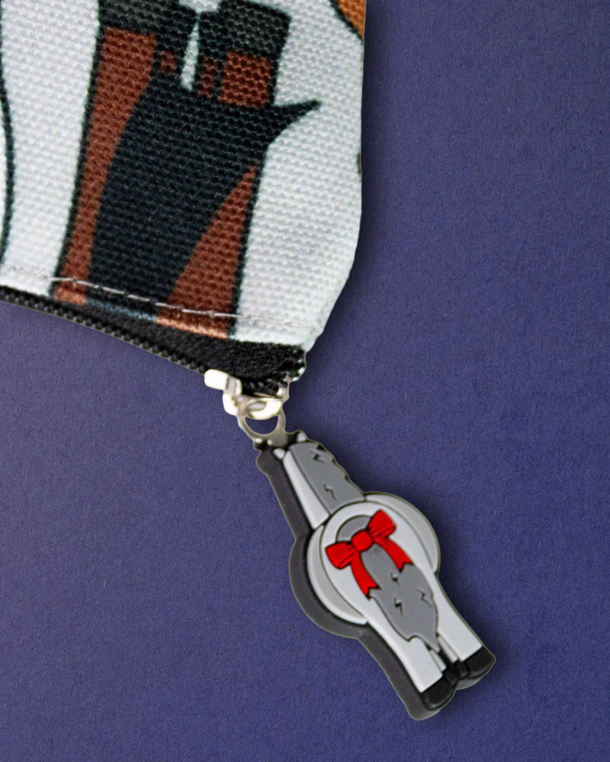 Bad pony zip pull charm, a grey horse rear with a red bow, hanging from the Butts pouch zip