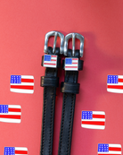 Black leather flag spur straps flat-laid on a red US flag icon backdrop