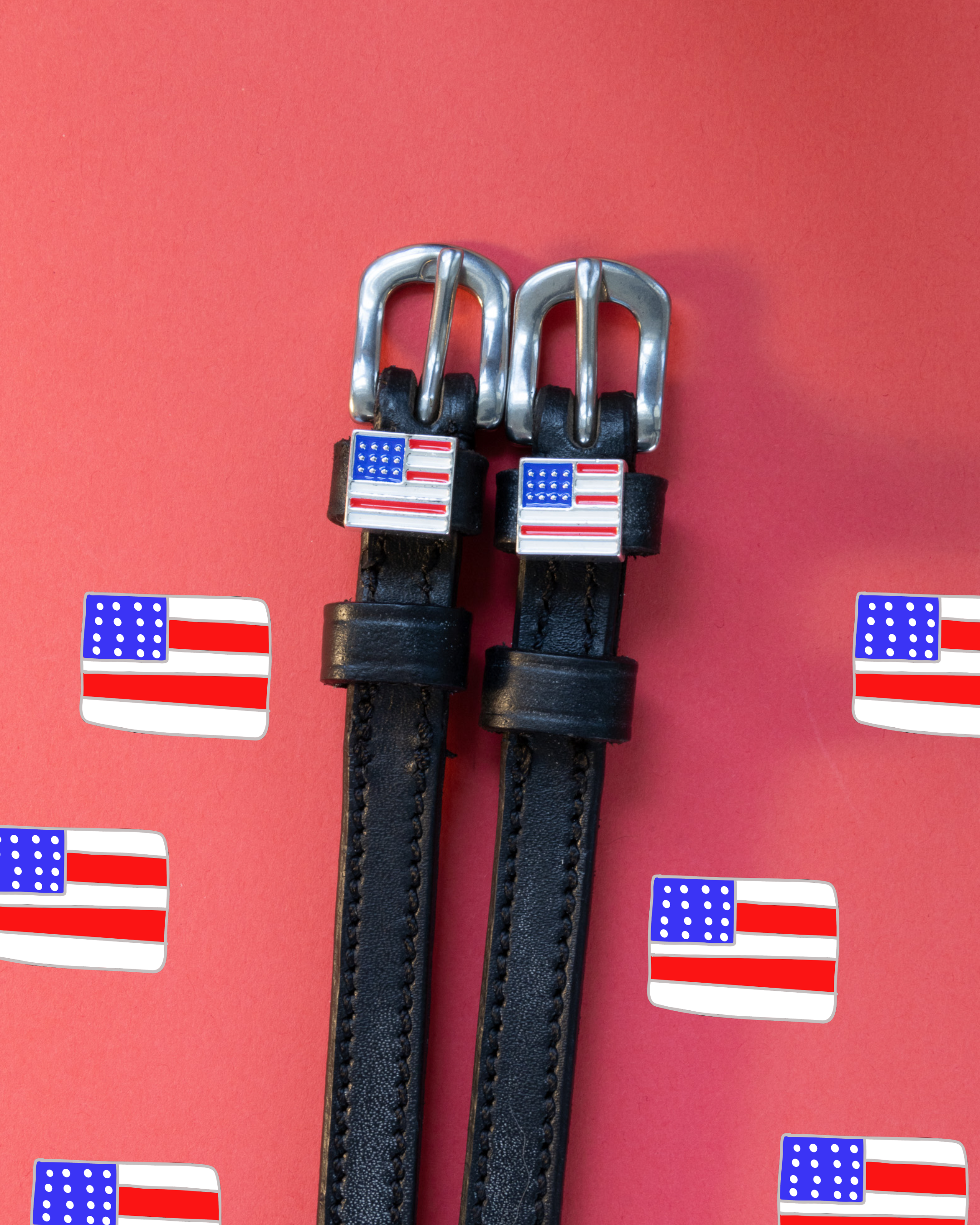Black leather flag spur straps flat-laid on a red US flag icon backdrop