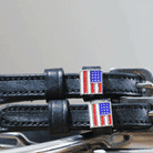 Close-up of American flag charms and silver buckles on black leather spur straps