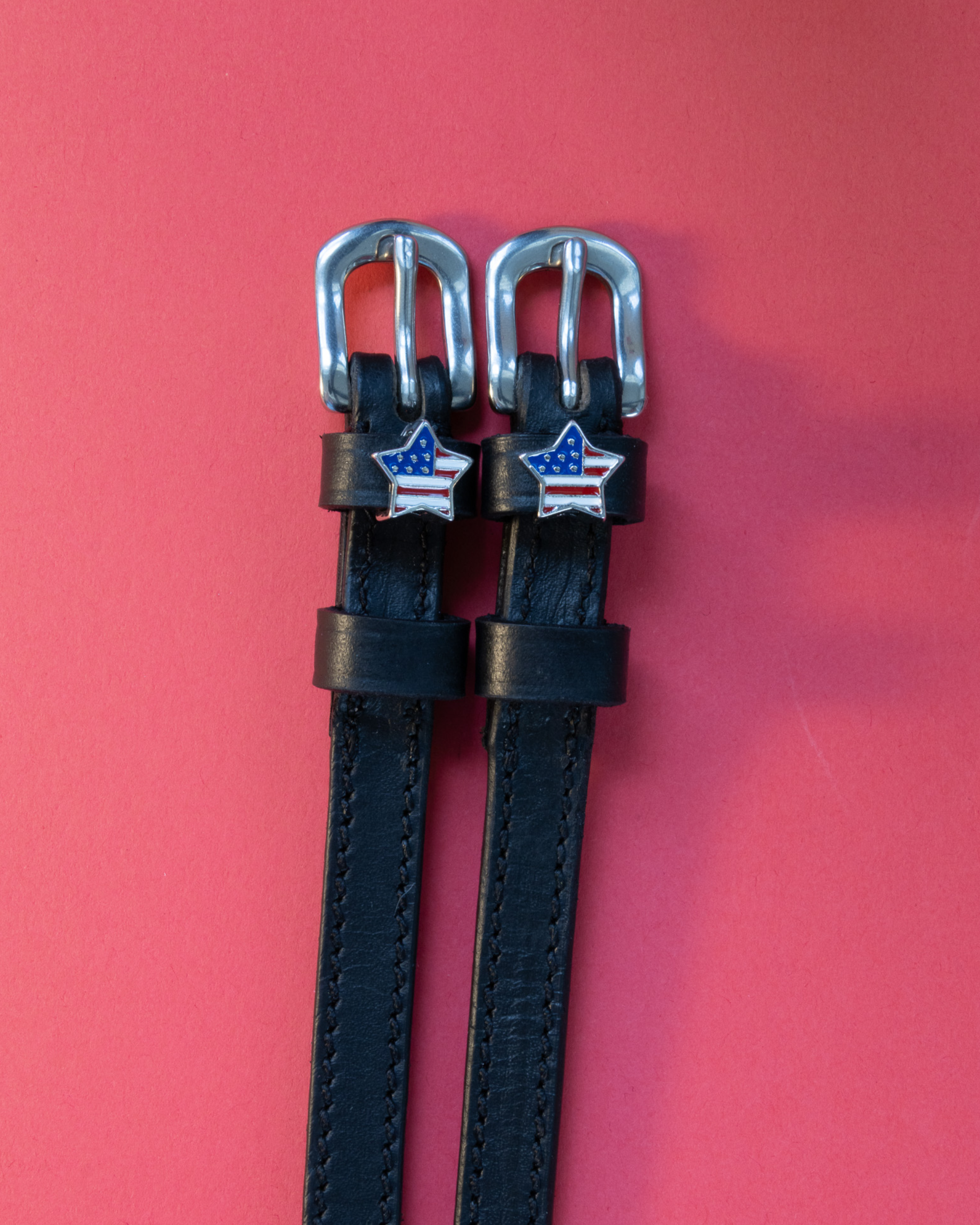 Pair of black leather American star spur straps with silver buckles on coral