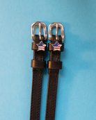 Brown leather American star spur straps with silver buckles on a light blue background