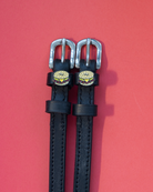 Pair of black leather ManeJane spur straps with bagel sandwich charms on pink