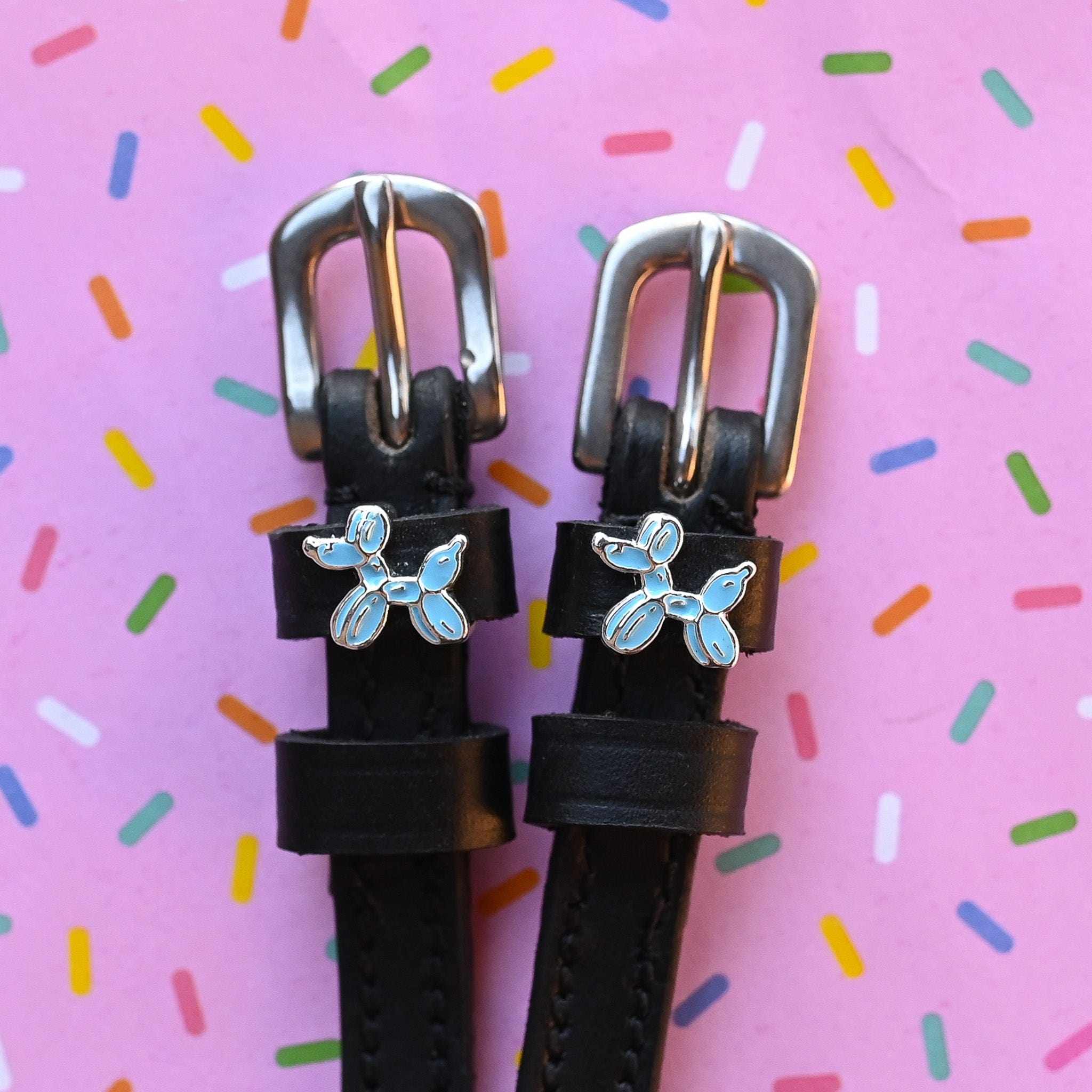 Balloon dog spur straps in black leather on a pink sprinkle confetti background