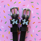Balloon dog spur straps in black leather on a pink sprinkle confetti background