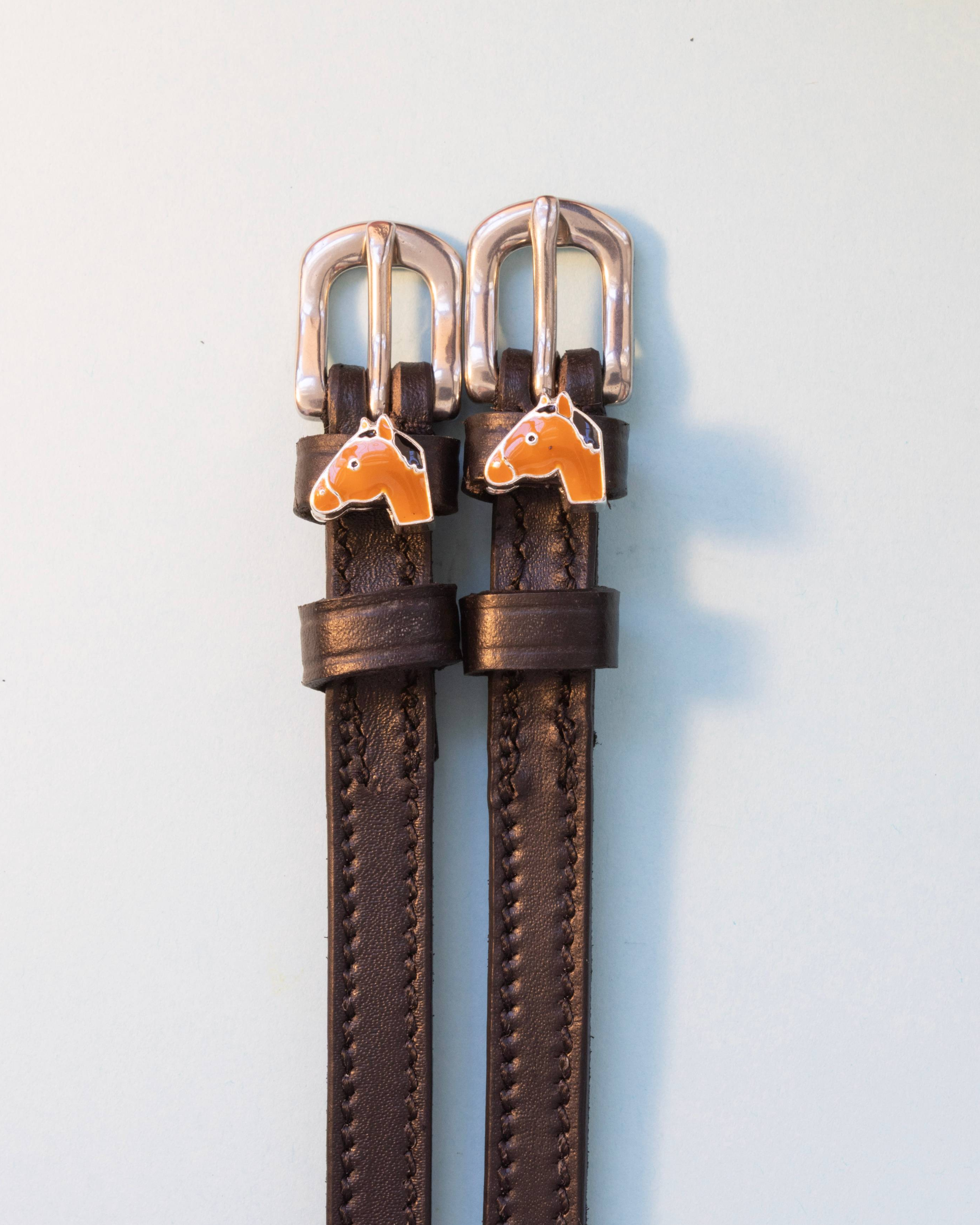 Brown leather spur straps with silver buckles and tan horse-head charms