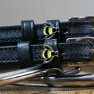 Close-up of silver-and-yellow bee charms on black leather ManeJane spur strap keepers