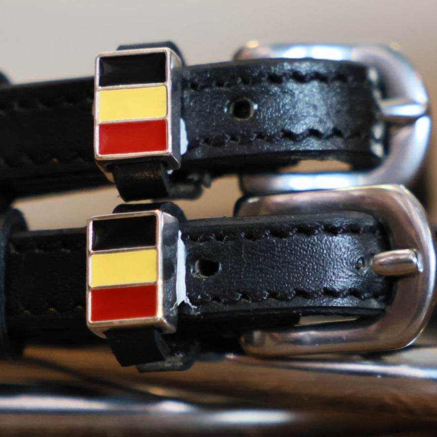 Close-up of black-yellow-red Belgian flag charms on black leather spur straps
