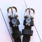 Blue ribbon rosette spur straps with silver buckles on white-painted wood planks