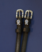 ManeJane blue-ribbon spur straps with silver buckles laid flat on navy blue