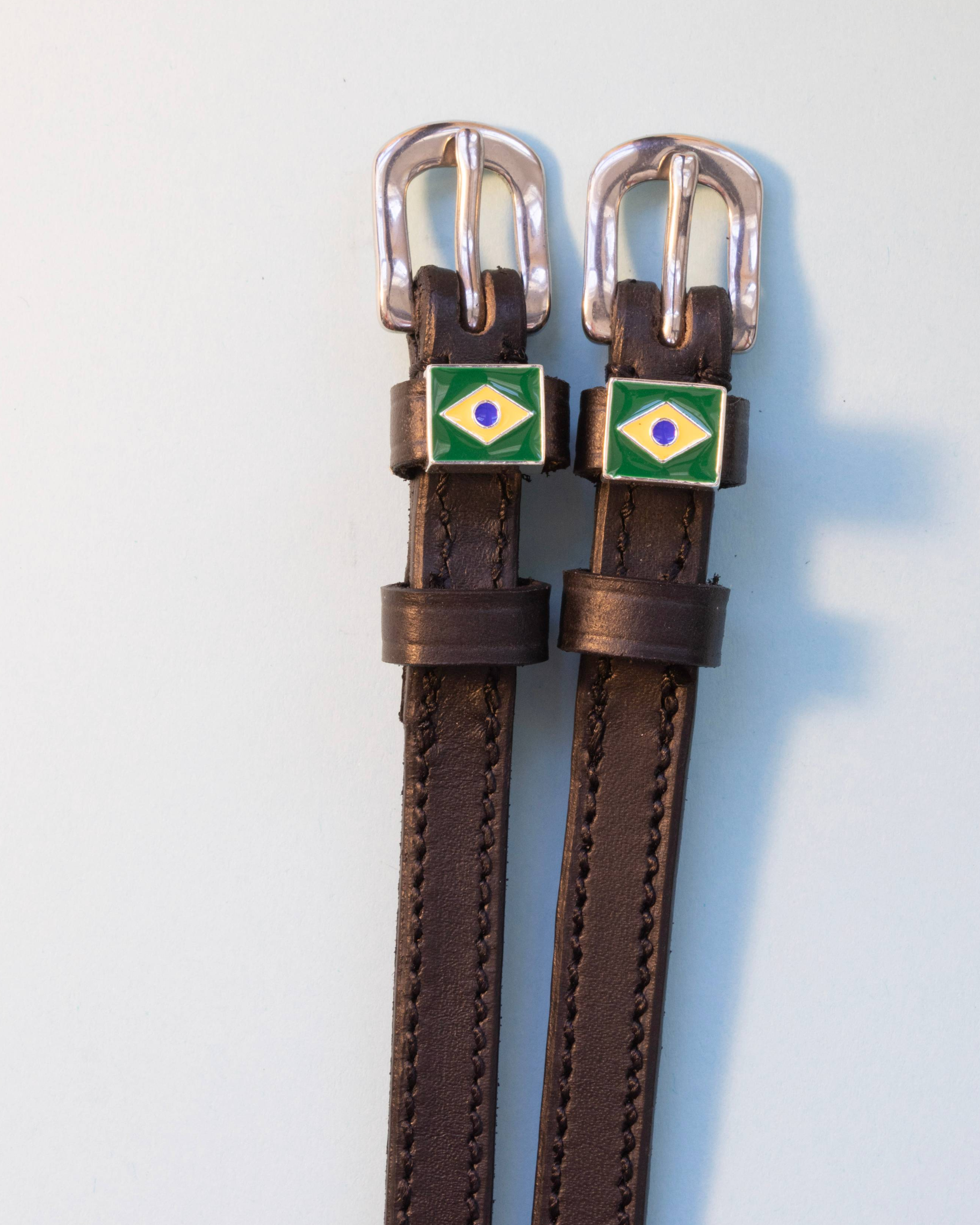 Brown leather ManeJane Brazil flag spur straps with silver buckles on pale grey