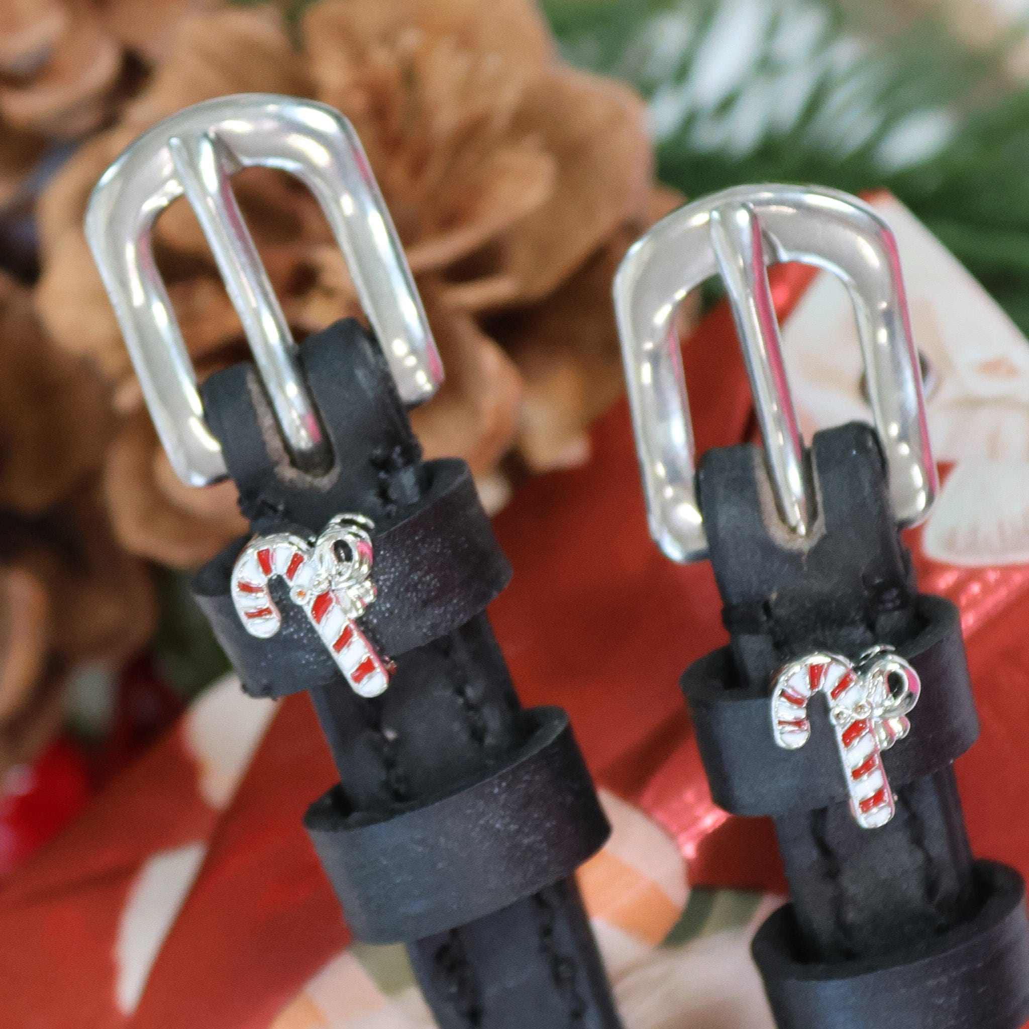 Candy cane charm spur straps styled with pinecones and greenery in a festive scene