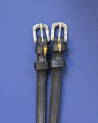 Pair of black leather spur straps with silver buckles and carrot charms on a blue background