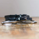 Black leather cash money spur straps coiled beside a spur on wood