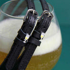 ManeJane champagne spur straps draped over a glass of bubbly on teal